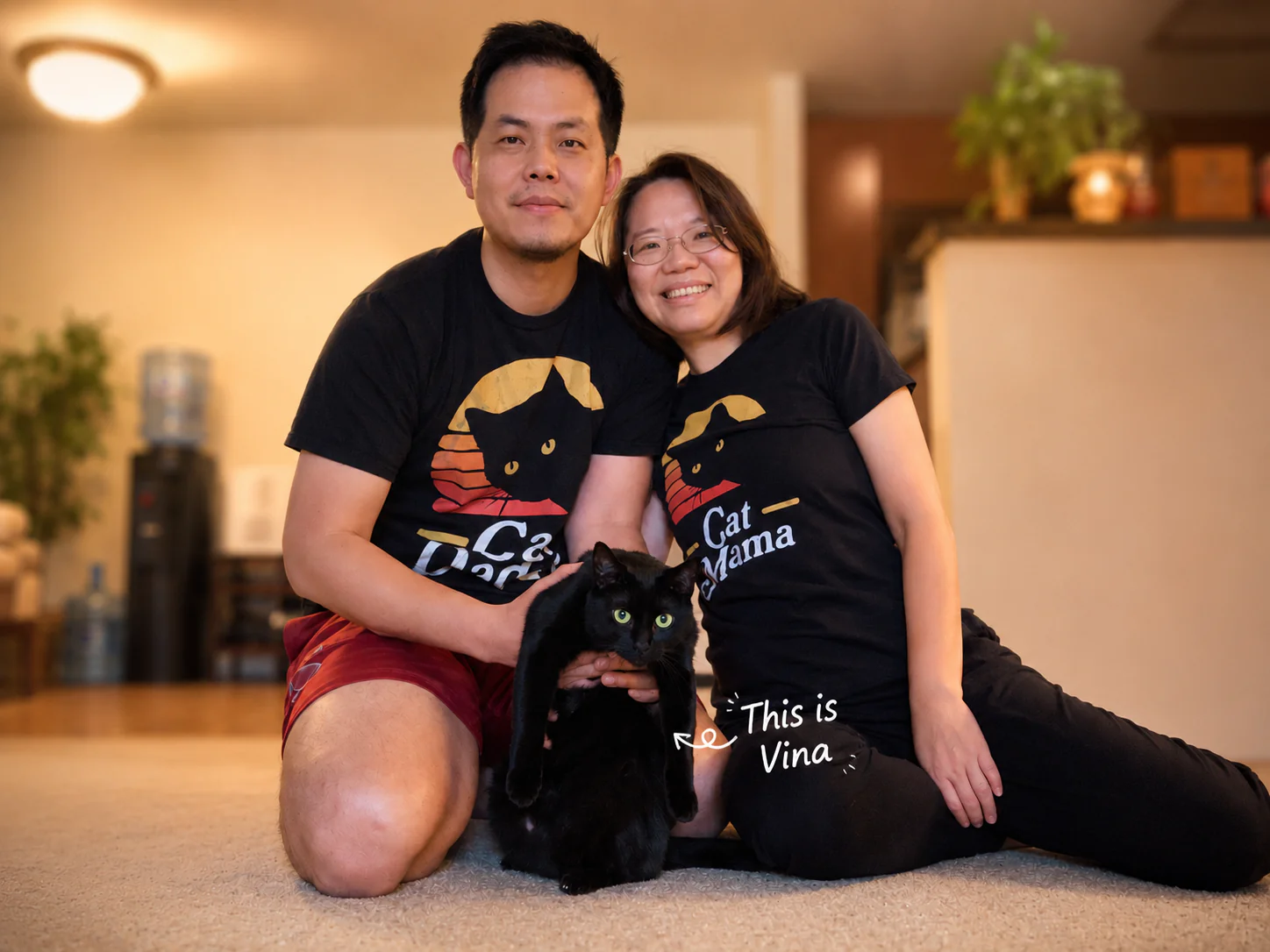 Jack and Winnie in matching Cat Dad and Cat Mama tees, holding Vina, their black cat