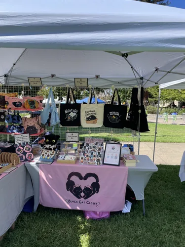The front of our booth with the Nugget Thief, Shipping: Expensive, and Duckie Is My Best Friend tote bags hanging on the grid wall