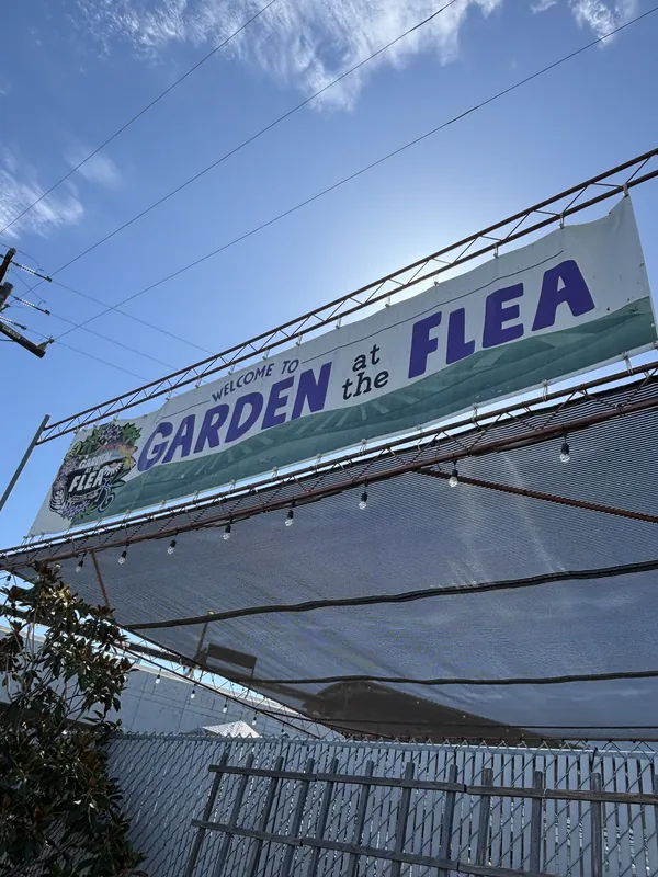 The "Welcome to Garden at the Flea" banner over the market entrance under a blue sky