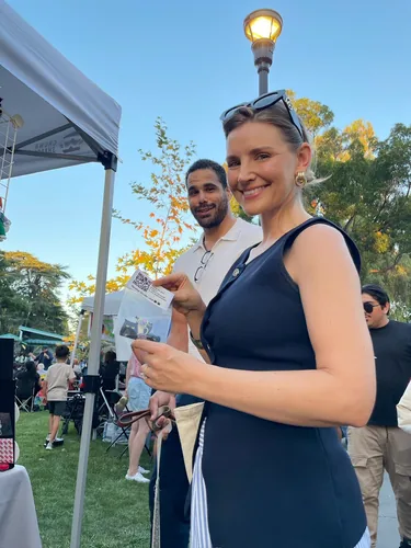 A customer at the booth holding up a black cat enamel pin in its Nyangi Studio USA packaging