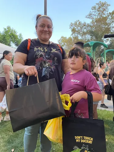 A mom and her daughter on the lawn, the girl carrying a Don't Touch My Duckie tote bag