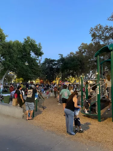 Families filling the playground and lawn at Todos Santos Plaza in the early evening