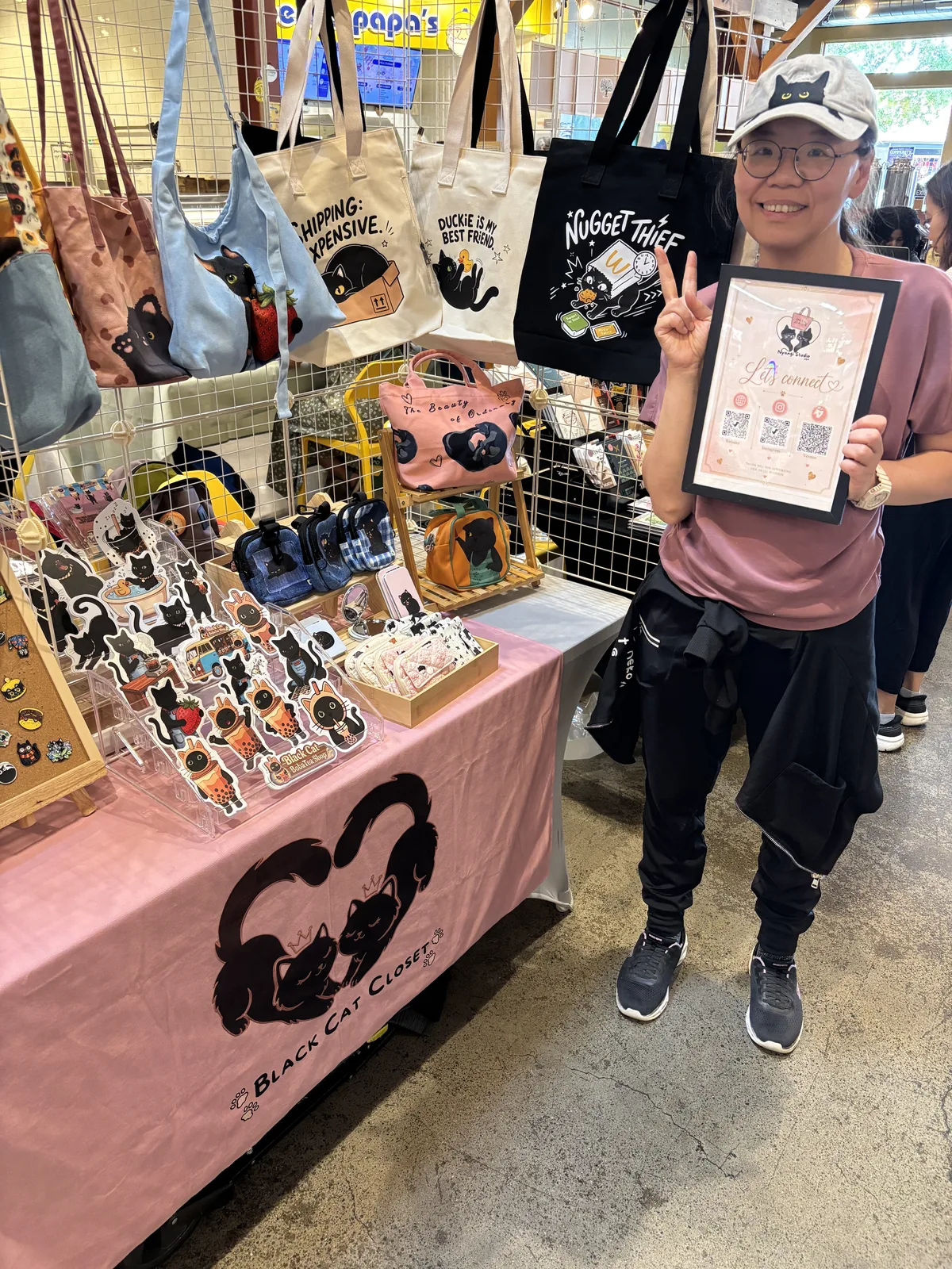 Winnie holding our "Let's connect" sign at the Nyangi Studio USA booth during First Fridays at Castro Valley Marketplace