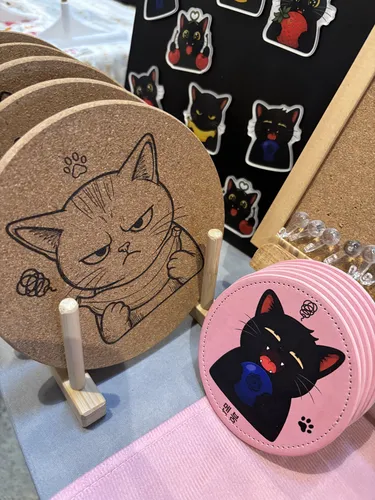 Cork cat coasters and pink leather cat coasters beside black-cat sticker sheets