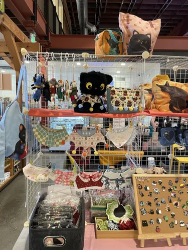Cat bandanas and collars on the grid wall, with wool-felt cat figures and a black cat plush above
