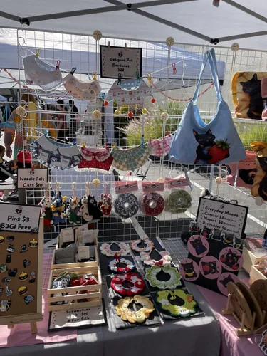 Designed pet bandanas strung across the grid wall above crochet collars, scrunchies, and wool-felt cats