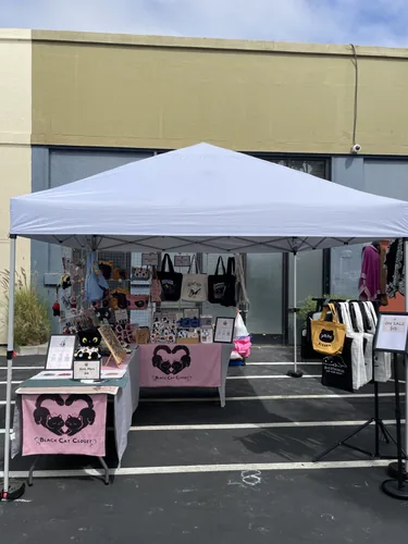 The white pop-up tent and Black Cat Closet banners seen from the aisle at Head West Marketplace
