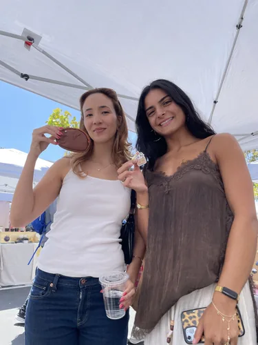 Two customers showing off a leather cat coin purse and a die-cut sticker they picked out