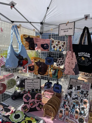 Illustrated cat bags including the blue strawberry shoulder bag and sleeping black cat pouches