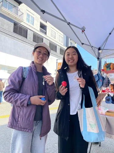 Two friends each holding a capsule from our capsule machine, one with a new keychain clipped on