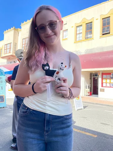 A customer holding two wool-felt cat ornaments, one black and one calico